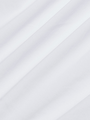 A close-up of the Sarai Off-the-Shoulder Tops smooth organic cotton fabric shows diagonal, soft folds creating subtle shaded lines across the surface.