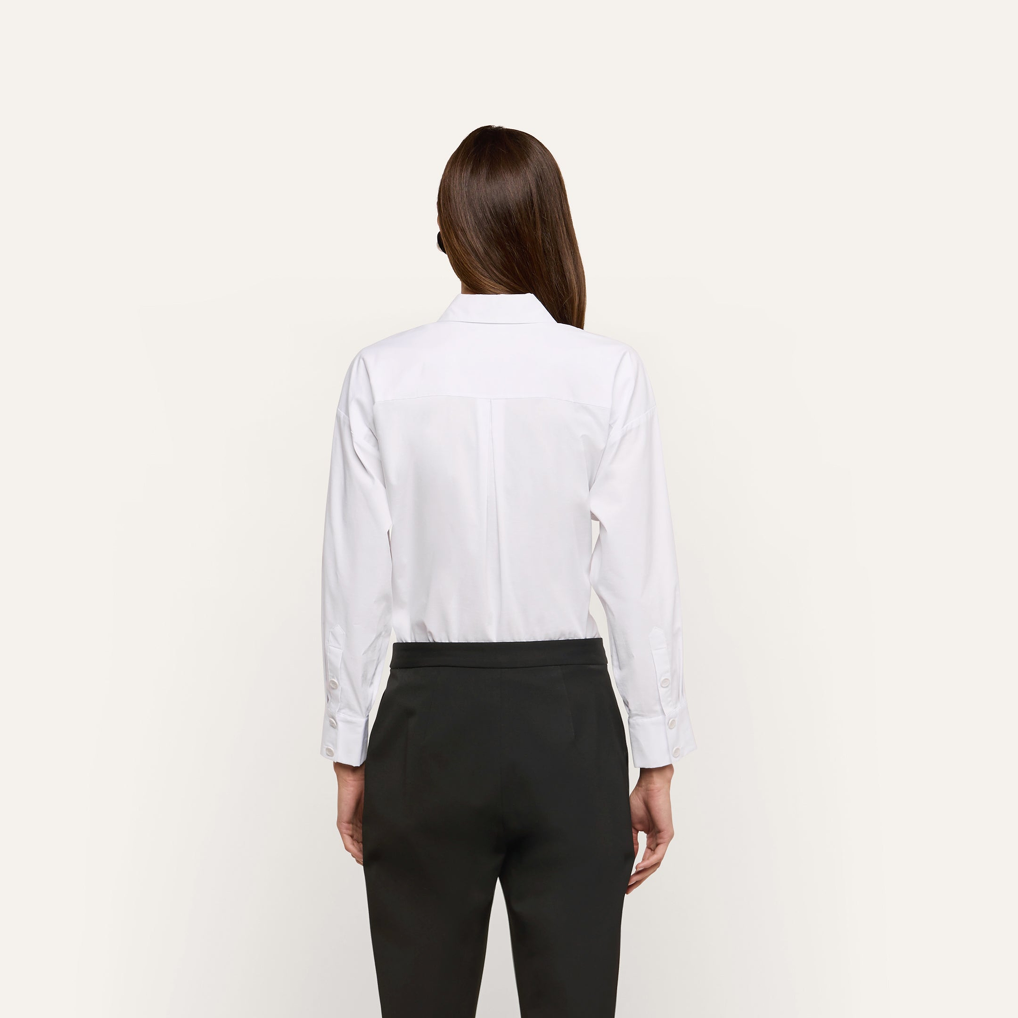 Back view of a person wearing a white Rylie Poplin Shirt tucked into black trousers.