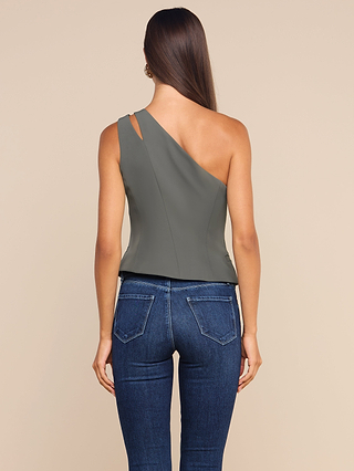 A woman with long brown hair stands with her back to the camera against a plain beige background, wearing the Zinnia One-Shoulder Top in gray—sleeveless with subtle sculptural tailoring—paired with blue jeans.