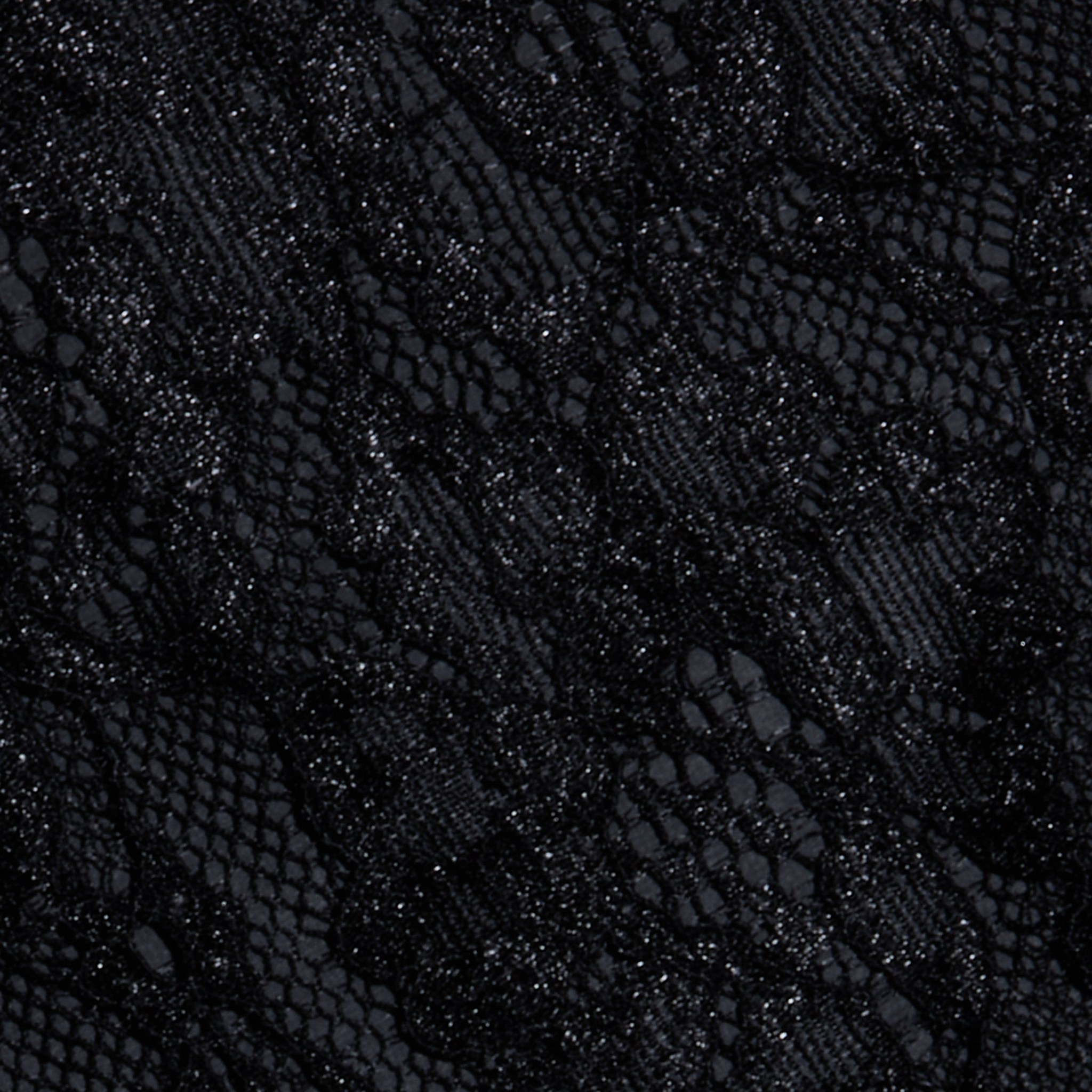 Close-up of the Henriette Cropped Lace Tops intricate black lace fabric, showcasing a delicate floral pattern with a combination of sheer and opaque textures. The material offers an elegant appearance with subtle shine in select areas, making it perfect for creating a sophisticated cropped top with refined details.