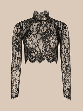 The Henriette Cropped Lace Top features a black, long-sleeved design with a high neckline and scalloped hem, crafted from sheer floral lace and showcased on a plain beige background.