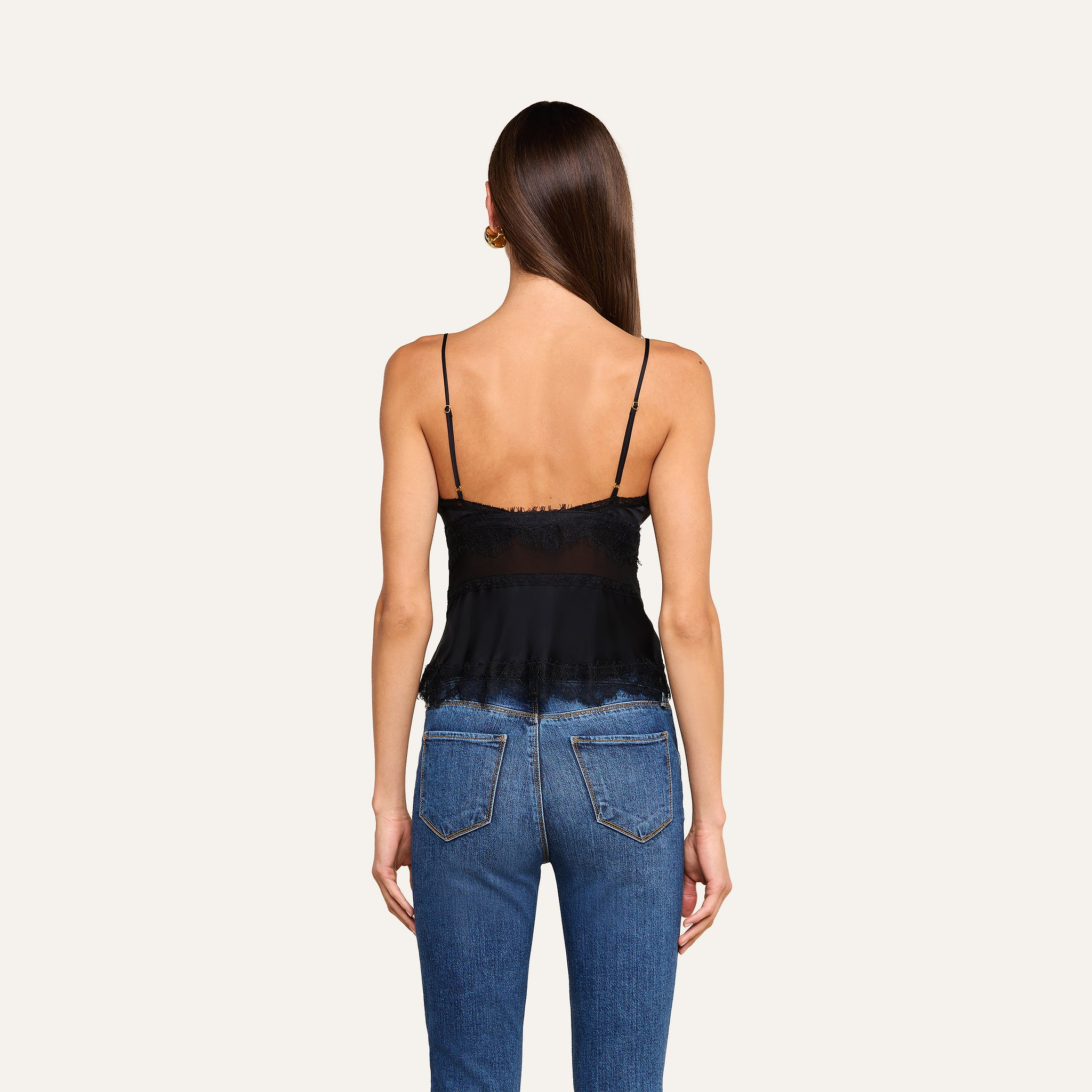 A woman with long straight hair is shown from the back, wearing the Elka Satin Lace Camisole and blue jeans, standing against a plain light background.