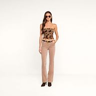 A fashion-forward woman wearing sunglasses, the Paulette Corset Top in a floral jacquard pattern, beige flared pants with a belt, and brown boots stands against a plain white background.