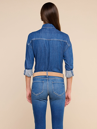 Wearing the Jorah Oversized Shirt with rolled-up sleeves and snap button closures, a person with long brown hair stands in blue jeans facing away from the camera against a beige background.