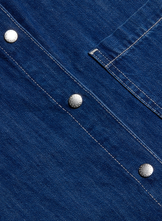Close-up of the Jorah Oversized Shirt’s featherweight denim fabric with diagonal seams and silver snap button closures, featuring white stitching and a small top-right pocket—perfect finishing touches for this roomy shirt.