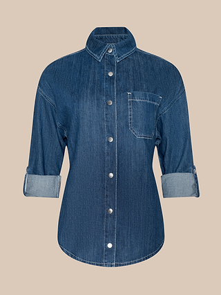 The Jorah Oversized Shirt is a blue featherweight denim button-up with rolled long sleeves, a single chest pocket, and a collar, presented on a plain beige background.