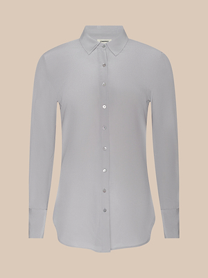 The Babette Silk Blouse is a light gray, long-sleeve crepe de chine button-up with a pointed collar and relaxed fit, shown against a plain beige background.