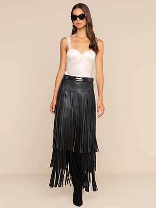 Woman wearing sunglasses, the Soleia Lace Camisole, and a black high-waisted leather skirt with long fringe details, standing against a plain beige background.