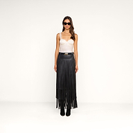 Woman wearing sunglasses, a white Soleia Lace Camisole, and a high-waisted long black fringe skirt with black ankle boots, standing against a plain white background.