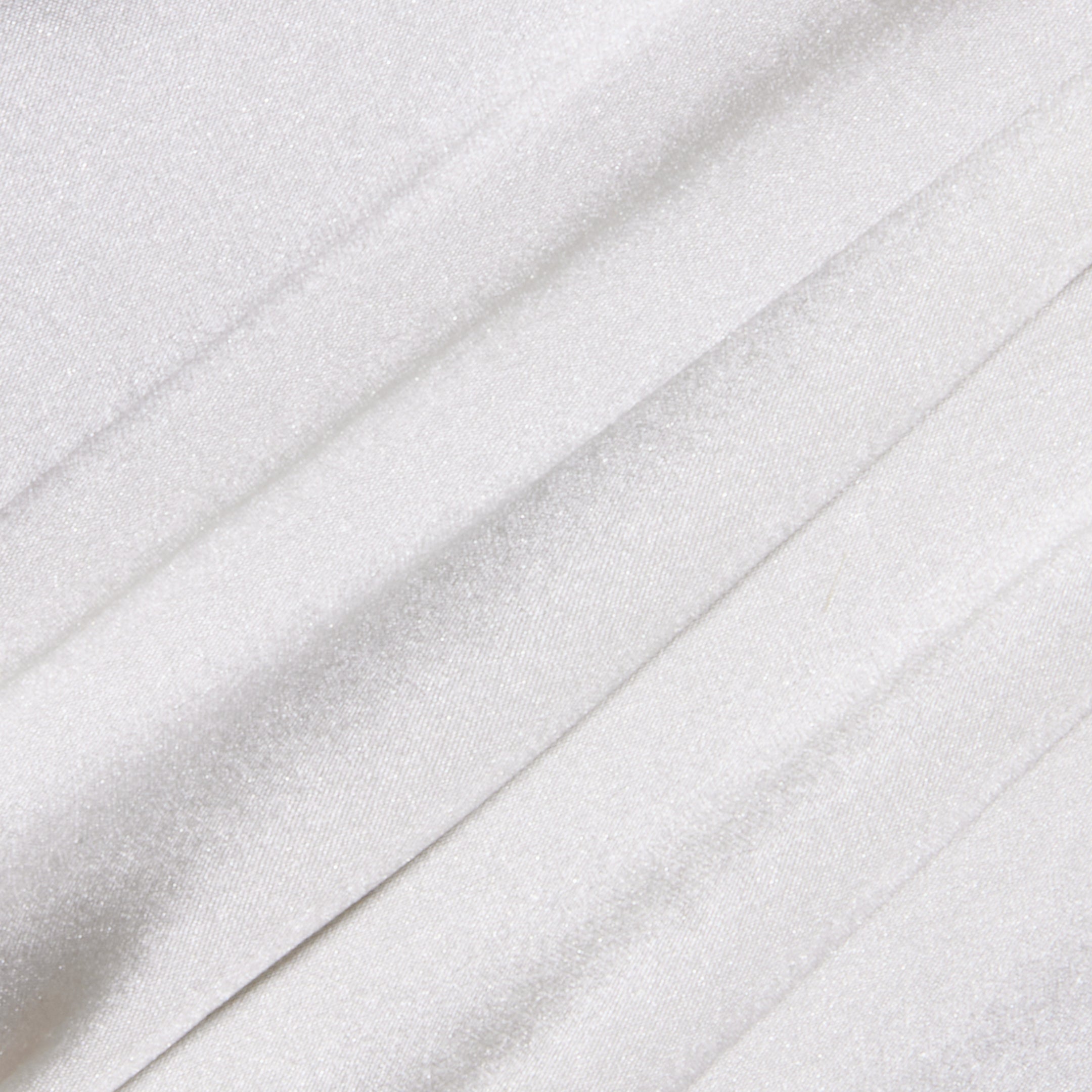 Close-up of the Soleia Lace Camisole’s white, slightly shiny silk charmeuse fabric featuring soft folds and subtle diagonal lines for a smooth and elegant texture.