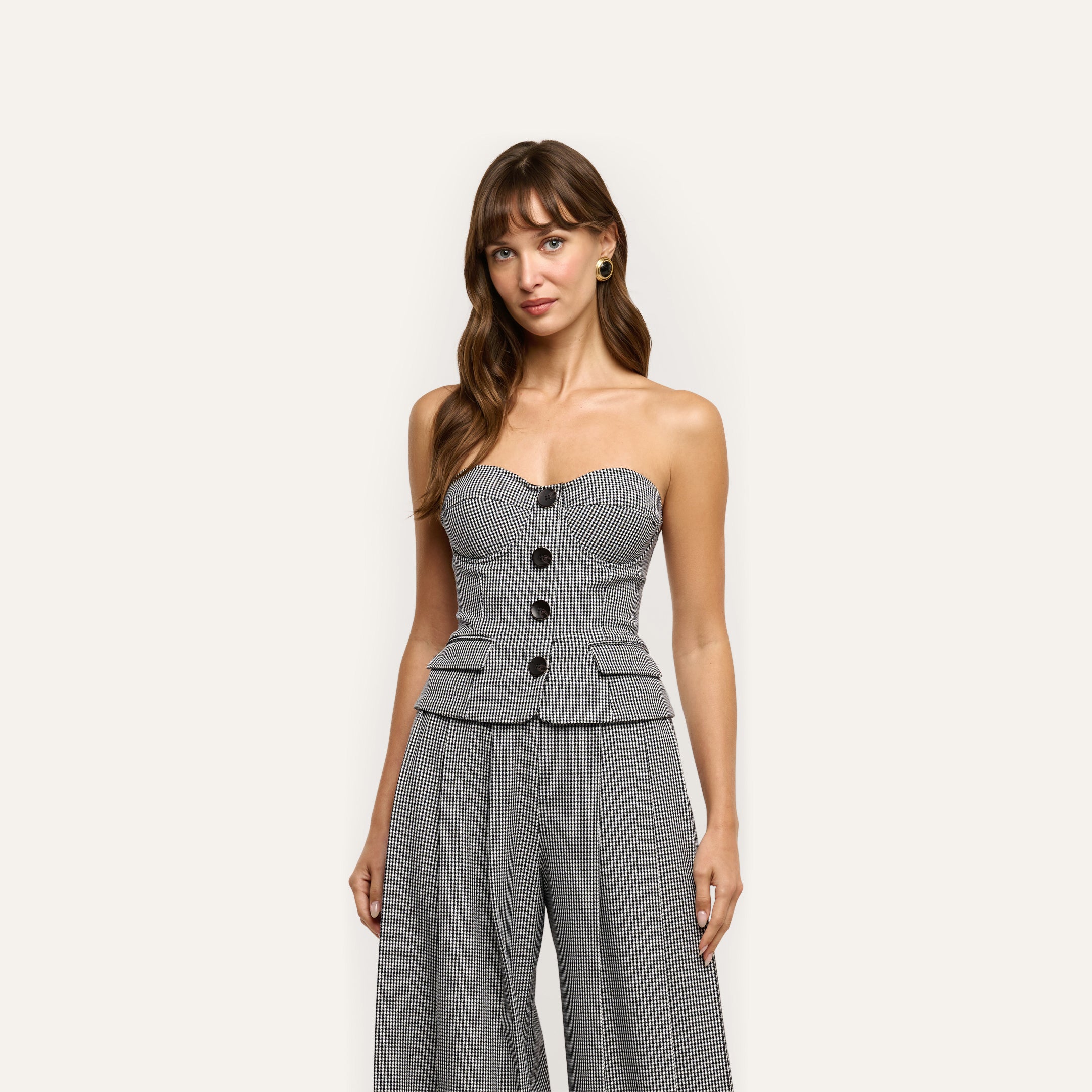 A woman wears a Genevieve Corset Top and matching wide-leg trousers in a black-and-white gingham pattern.