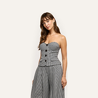 A person wearing the Genevieve Corset Top, a strapless, black and white houndstooth suiting corset with a buttoned front and a peplum hem.