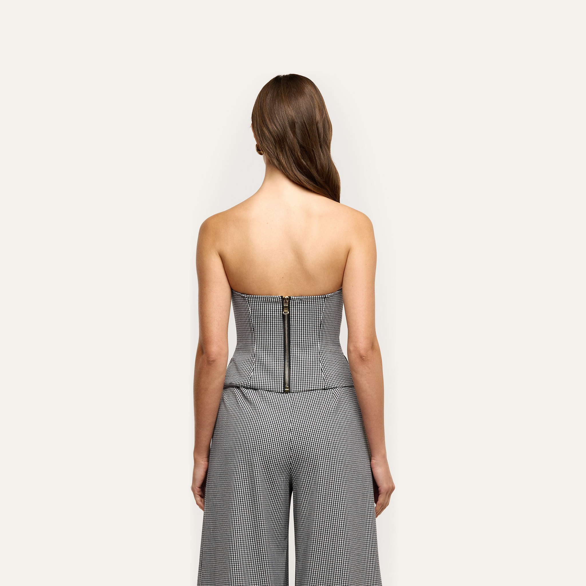 Back view of the Genevieve Corset Top in black and white gingham with houndstooth suiting details and a center back zipper, paired with matching wide-leg trousers.