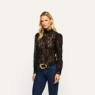 A woman wears an Amarenthe Lace Blouse, featuring a long-sleeved black corded lace mockneck, paired with dark blue jeans.