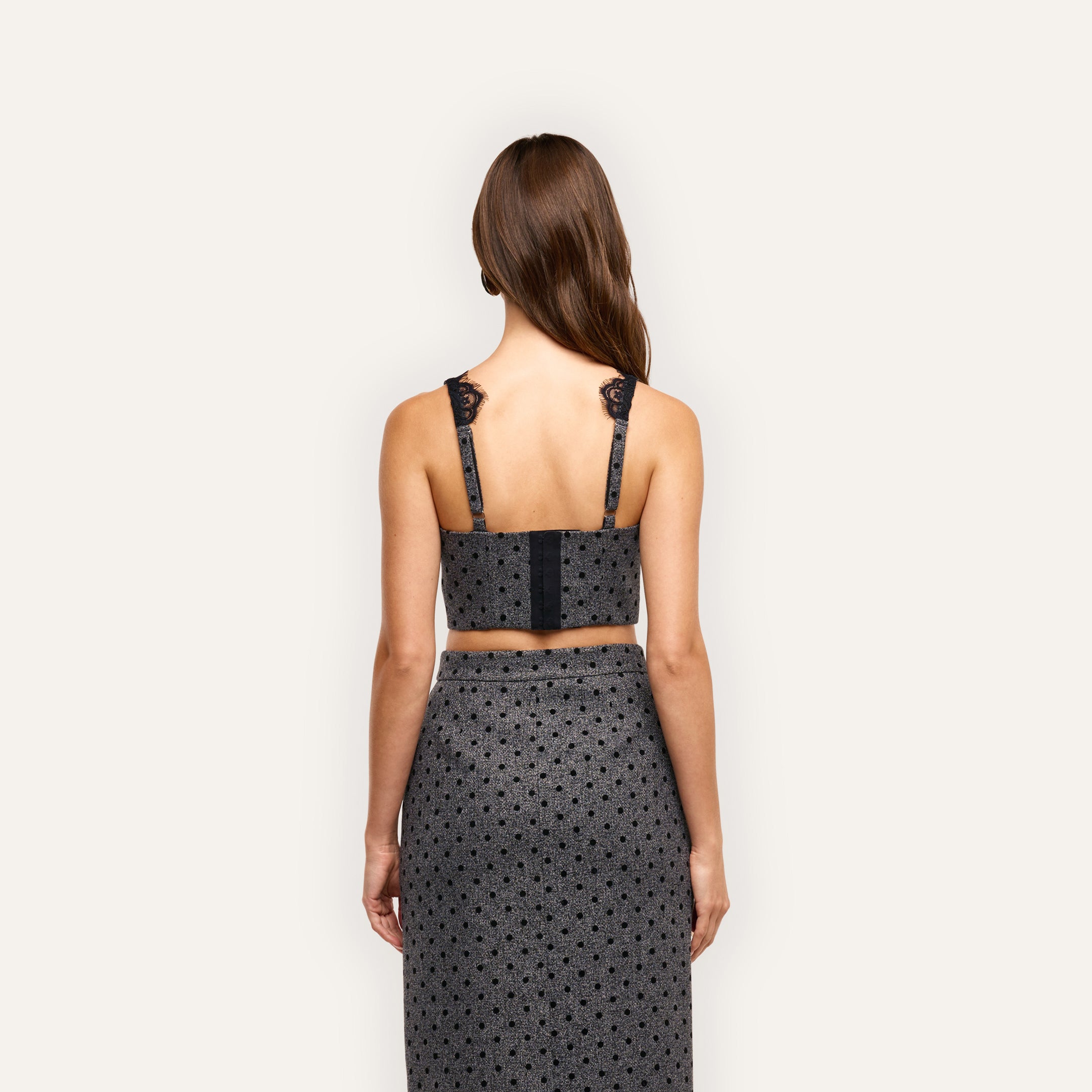 Back view of the grey polka-dot Oriane Bustier Top with built-in underwire and black lace trim on the straps, paired with a matching midi skirt.