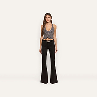 A person wears a hand-embellished Nixe Embellished Vest featuring a cropped, deep V-neck silhouette with small white dots, paired with black flare jeans and a black belt.