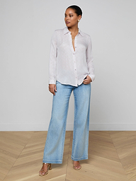 Wearing the Nina Silk Blouse in a relaxed fit, paired with light wash wide-leg jeans and sandals, a person stands against a plain white background, looking slightly to the side.