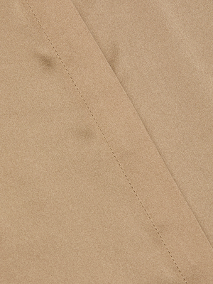 Close-up of the Bianca Silk Blouse in light brown charmeuse, featuring a diagonal seam with visible stitching that forms a subtle line across the smooth, slightly textured fabric.