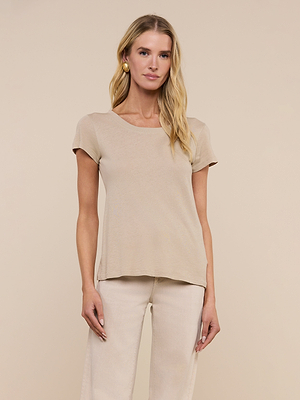 A woman with long blonde hair wears the Cory Cotton Scoopneck Tee in slim fit taupe and light pants, standing against a plain beige background. She faces forward, relaxed, with her hands at her sides.