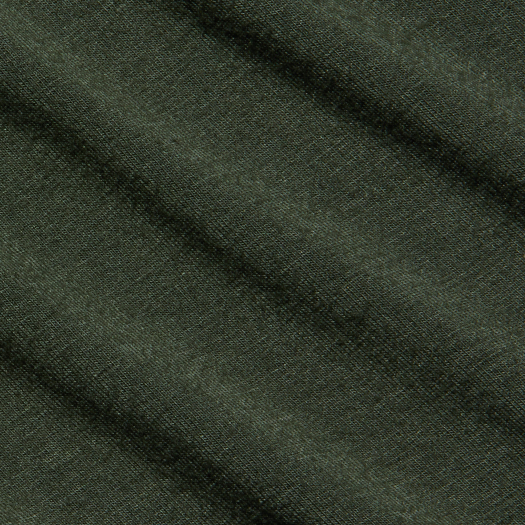 Rich dark green fabric of the Aja Turtleneck, featuring a soft knit texture and diagonal folds that create gentle shadows and highlights across its surface.