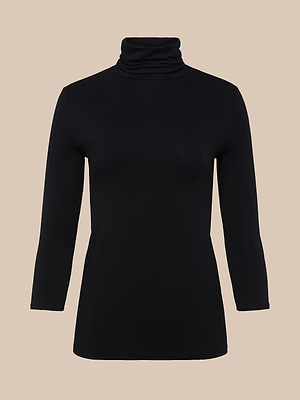 The Aja Turtleneck is a slim-fit black long-sleeve top made from soft microfiber, shown against a neutral beige background.