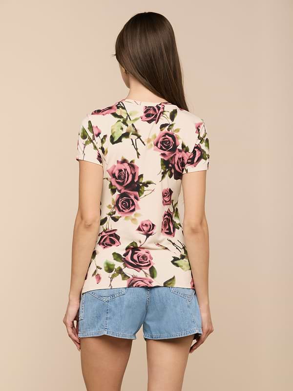 A person with long brown hair wears the Ressi Fitted Tee, a slim-cut, rose-patterned short-sleeve T-shirt made from stretch jersey knit, paired with denim shorts, standing with their back to the camera against a light background.