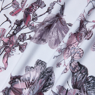 Close-up of the Ressi Fitted Tee in stretch jersey knit, featuring a floral and butterfly print in purple, mauve, and black on a white background. The soft folds highlight the tees intricate botanical and insect design.