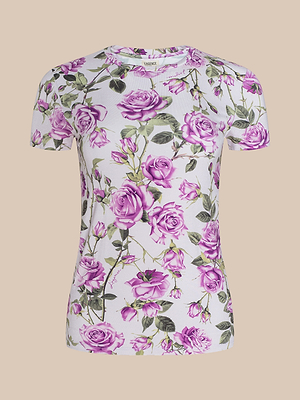 The Ressi Fitted Tee is a short-sleeved white top made from soft stretch jersey, featuring an all-over purple rose and green leaf print. Shown on a beige background, this bestselling tee adds standout style to any look.