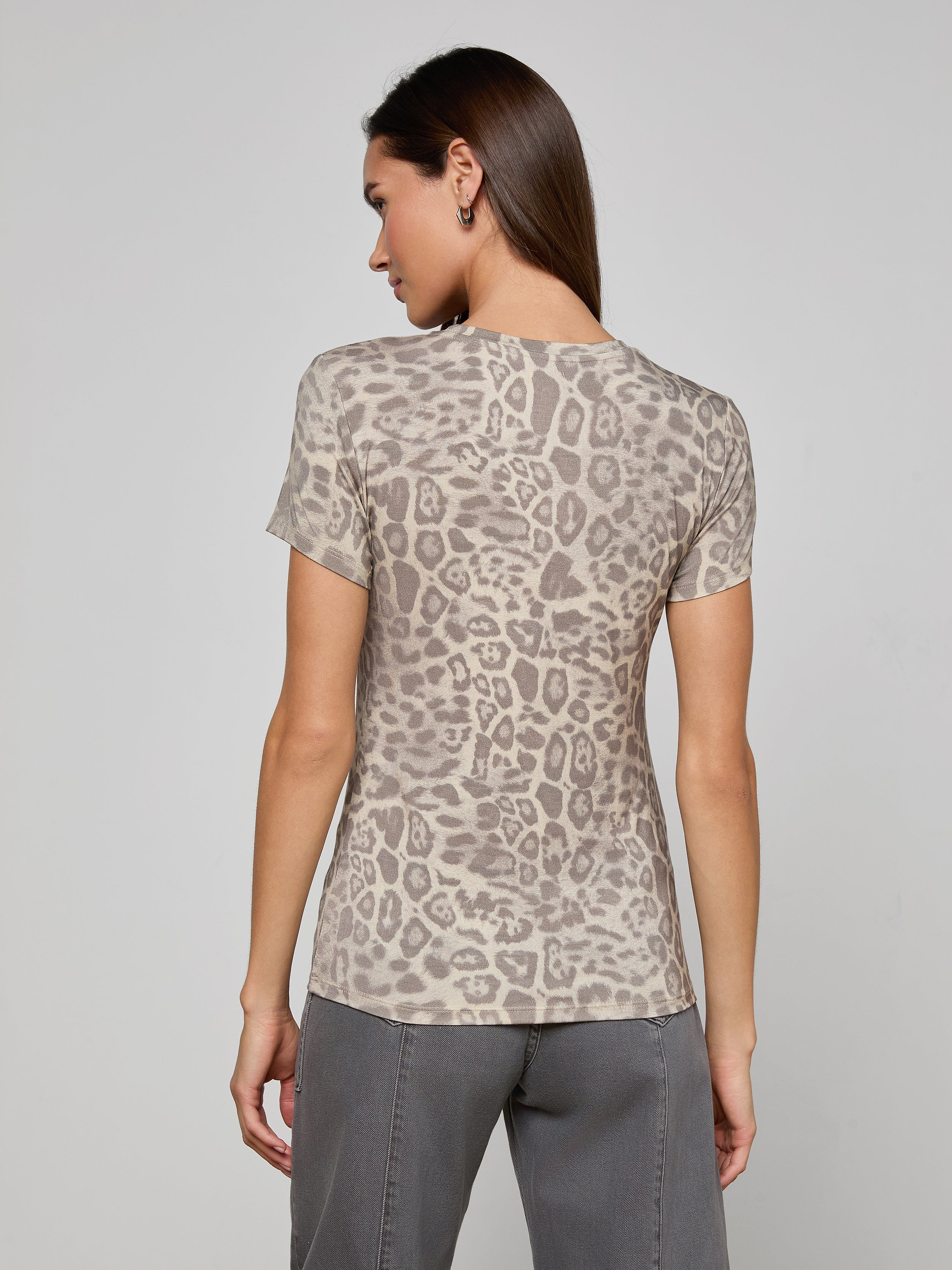 A woman stands with her back to the camera, wearing the bestselling Ressi Fitted Tee in gray leopard print and gray pants, against a plain light background.
