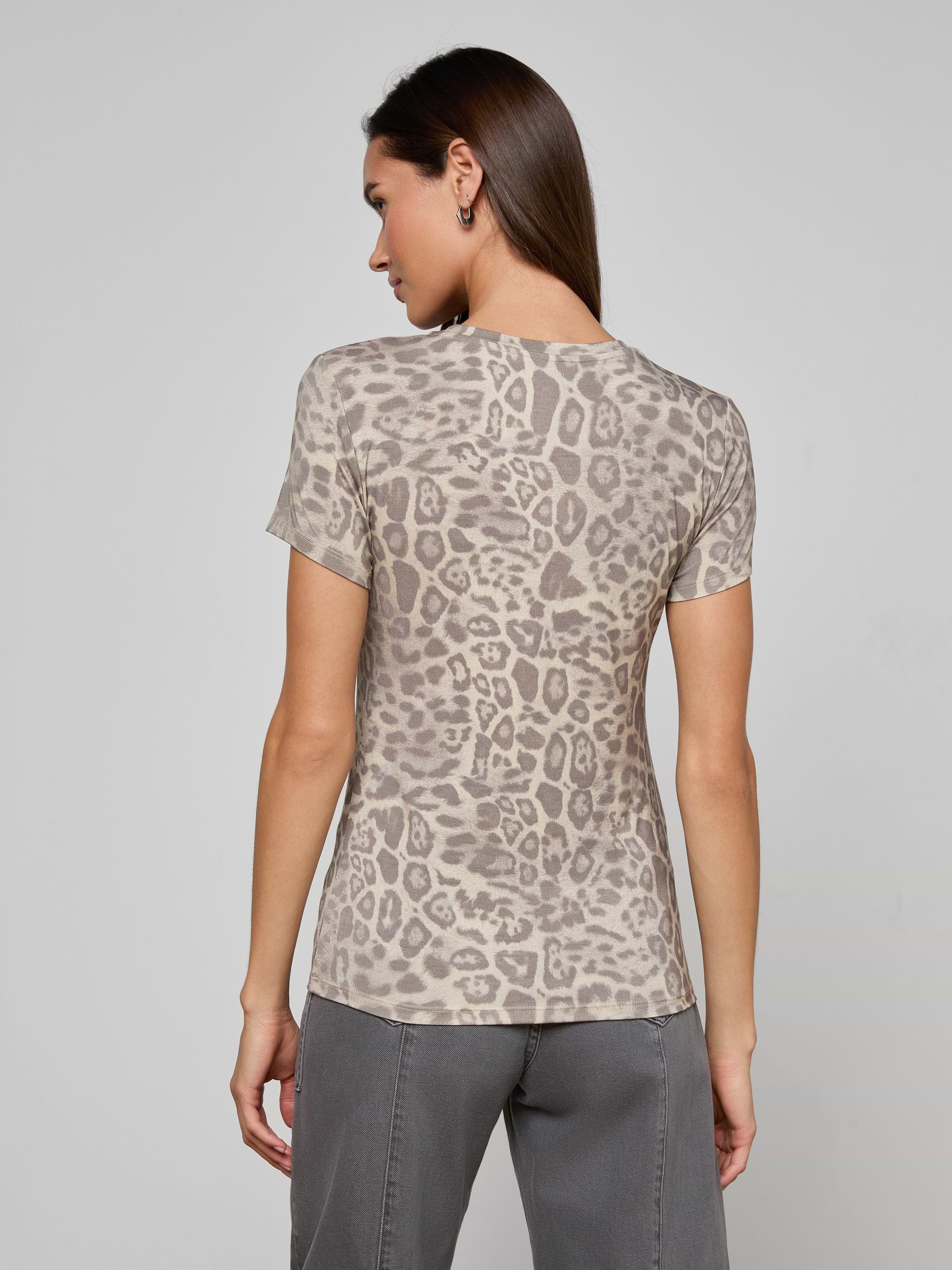 A woman stands with her back to the camera, wearing the bestselling Ressi Fitted Tee in gray leopard print and gray pants, against a plain light background.
