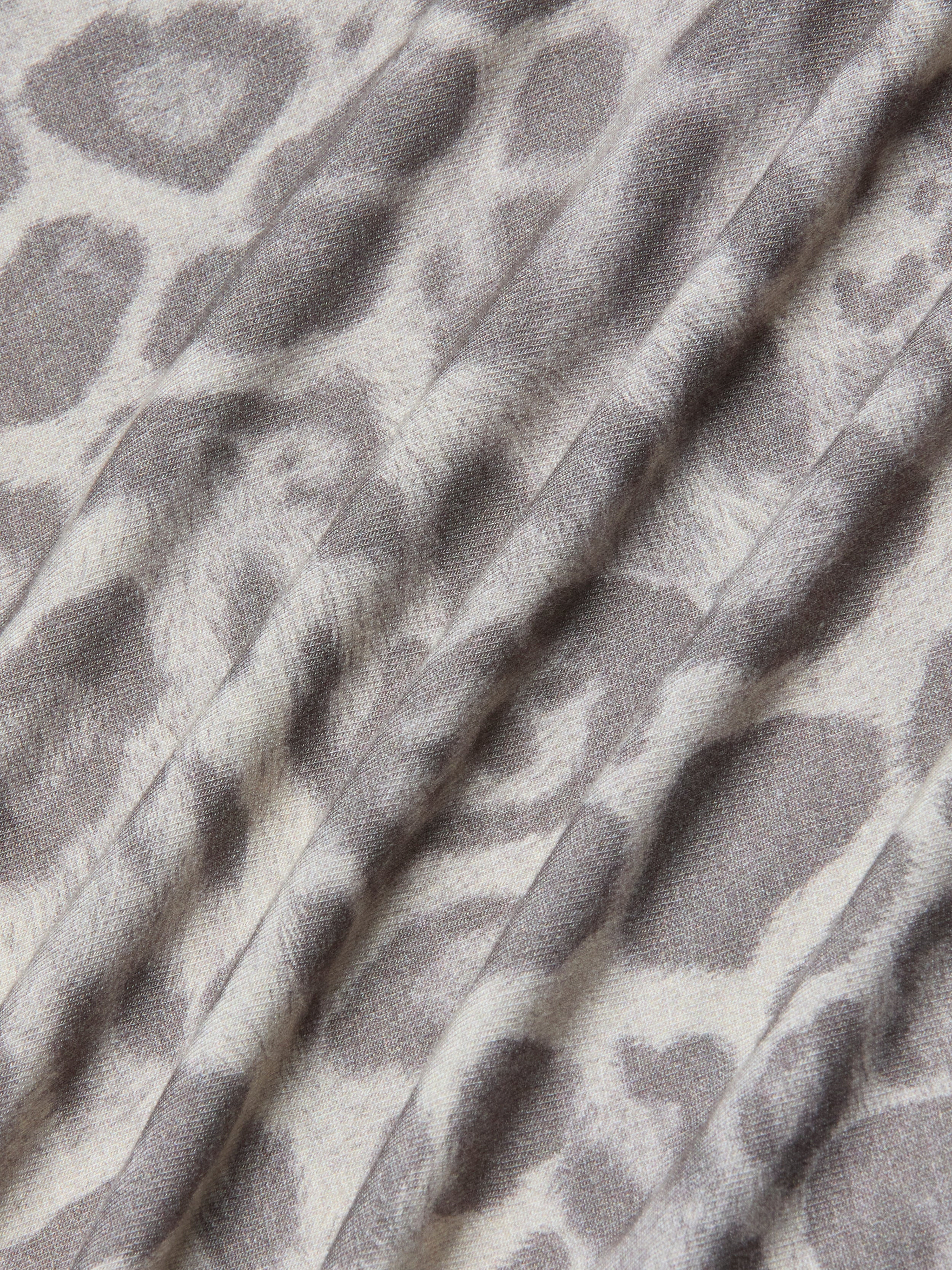 A close-up of the Ressi Fitted Tee showcases its stretch jersey knit fabric in a gray leopard print pattern, featuring soft folds and a slightly textured surface.