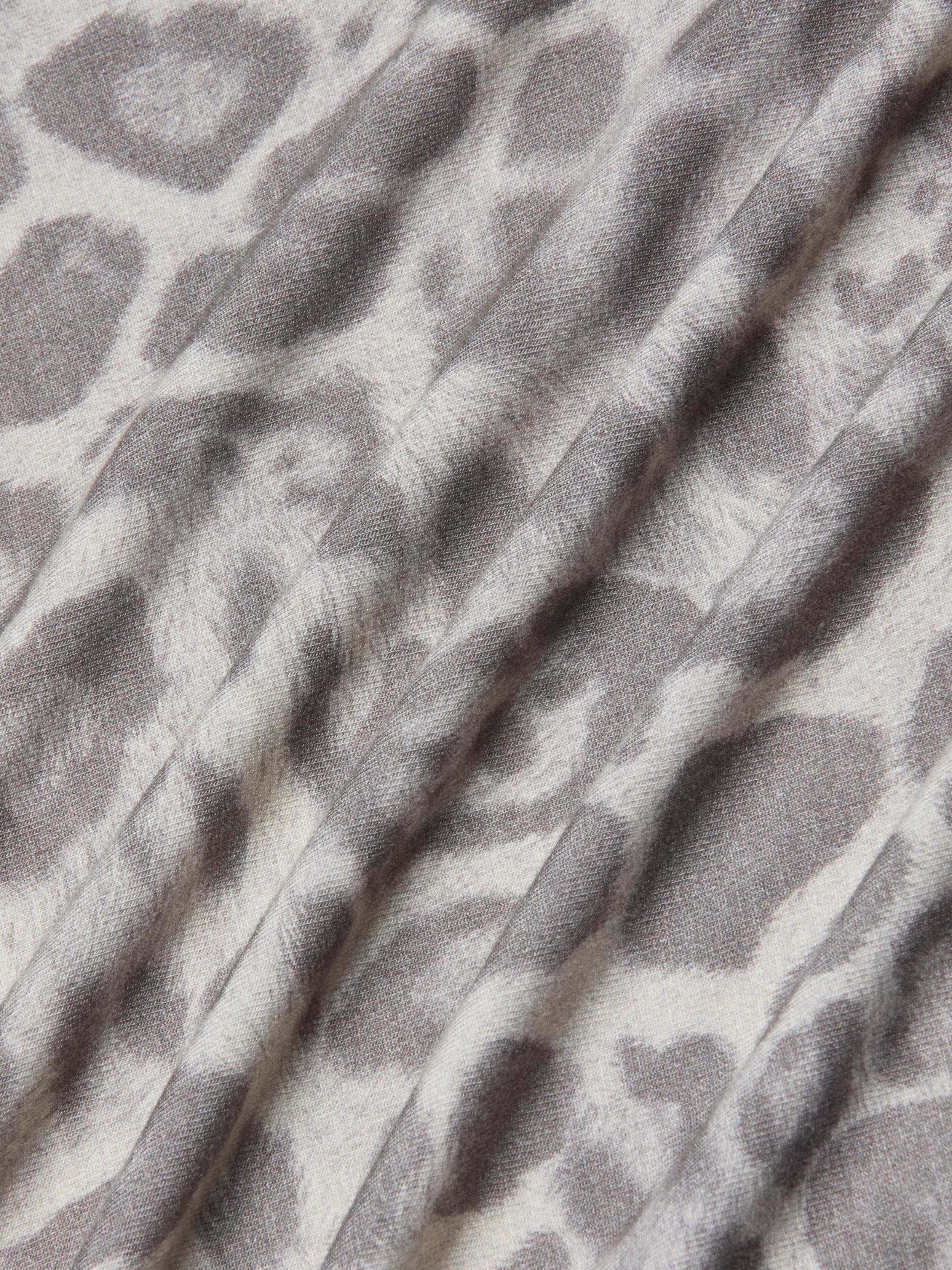 A close-up of the Ressi Fitted Tee showcases its stretch jersey knit fabric in a gray leopard print pattern, featuring soft folds and a slightly textured surface.