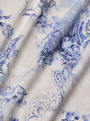 A close-up of fabric with a blue floral paisley print on light beige, softly folded for texture and subtle shadows—ideal for the Ressi Fitted Tee.
