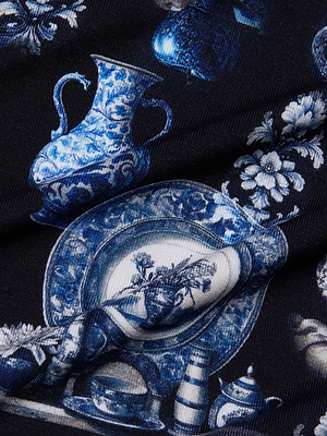 The L'AGENCE Ressi Fitted Tee features artistically arranged blue and white porcelain motifs—plates, vases, and pitchers—on dark stretch jersey knit with floral accents for an elegant, vintage-inspired look.