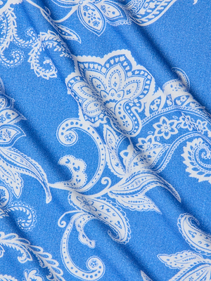 Blue stretch jersey knit fabric with a white paisley floral and leaf pattern. Subtle folds add texture and shadow—ideal for the Ressi Fitted Tee or other slim cut styles.