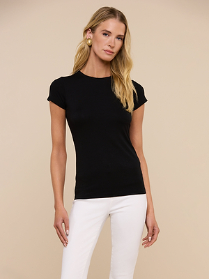 A woman with long blonde hair wears the Ressi Fitted Tee in black and white pants, standing against a beige background and looking at the camera with a neutral expression.