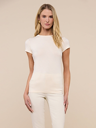 A woman with long blonde hair stands against a plain, light background, facing forward with a neutral expression, wearing the Ressi Fitted Tee in vintage white and matching pants.