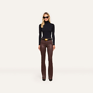 A woman in a slim fit Lani Turtleneck and brown leather pants with a belt stands against a plain white background, wearing sunglasses.
