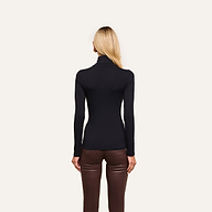 A woman with straight blonde hair wears the slim fit black Lani Turtleneck and brown leather pants, standing with her back to the camera against a plain light background.