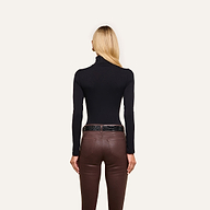 A woman with straight blonde hair models the slim fit Lani Turtleneck in black and brown pants, standing with her back to the camera against a plain white background.