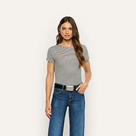 A woman wears a black and white striped ribbed knit Ressi Fitted Tee tucked into blue jeans with a black belt.