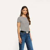 A woman wears a black and white striped ribbed knit Ressi Fitted Tee tucked into dark wash blue jeans with a black belt.