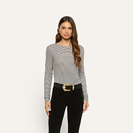 Woman wearing a slim-fit, long-sleeved black and white striped Tess Long Sleeve Tee tucked into black pants with a large gold-buckled belt.