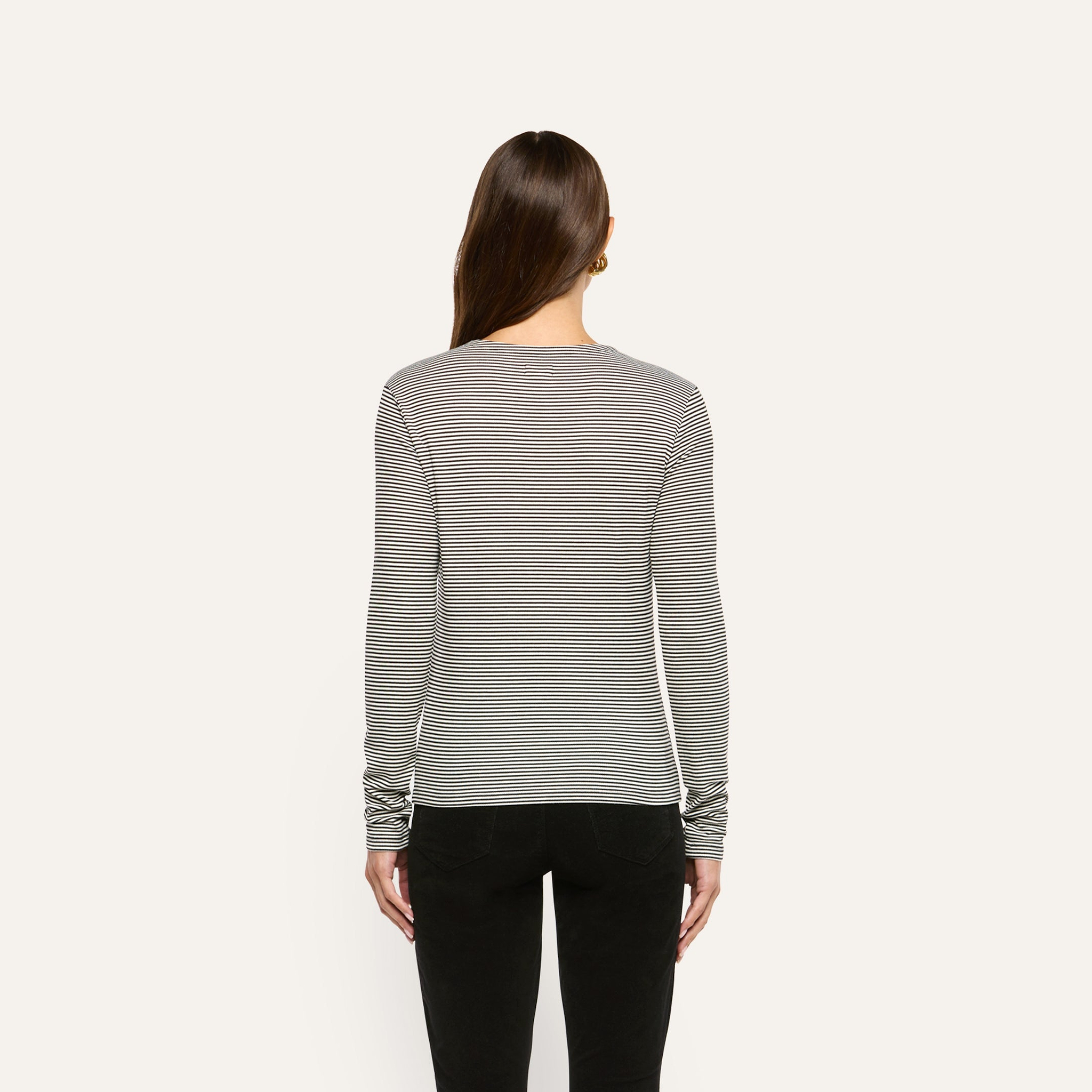 Back view of a person wearing a slim fit, black and white striped ribbed knit Tess Long Sleeve Tee tucked into black pants.