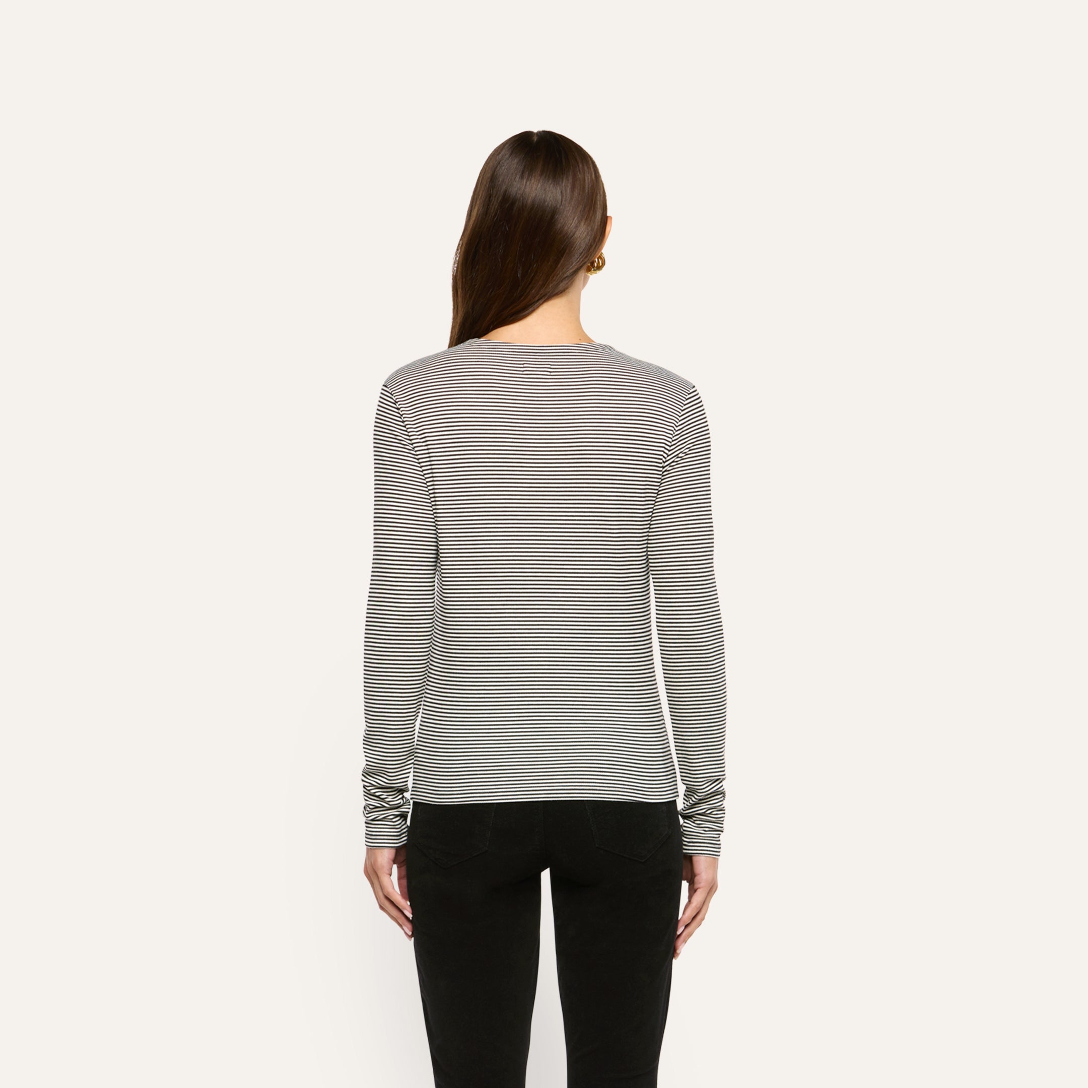 Back view of a person wearing a slim fit, black and white striped ribbed knit Tess Long Sleeve Tee tucked into black pants.