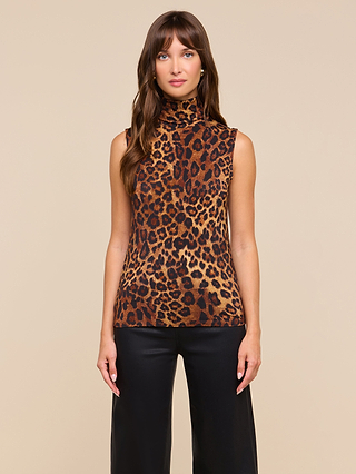 A woman with long brown hair stands against a plain beige background, facing forward with a neutral expression, wearing the Ceci Sleeveless Turtleneck—a slim fit leopard print top—paired with black pants.