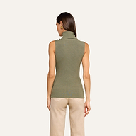 A woman stands facing away, wearing the Ceci Sleeveless Turtleneck in ash olive green and beige pants against a plain light background.