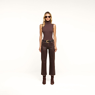 Woman wearing sunglasses, a Ceci Sleeveless Turtleneck in stretch rib knit brown, a brown belt, slim-fit high-waisted pants, and brown boots, standing against a plain beige background.