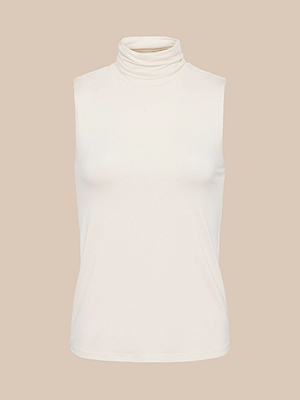 The Ceci Sleeveless Turtleneck in ivory is shown against a neutral beige background, featuring a smooth, slim-fit fabric with a high neckline and a clean, pattern-free design.