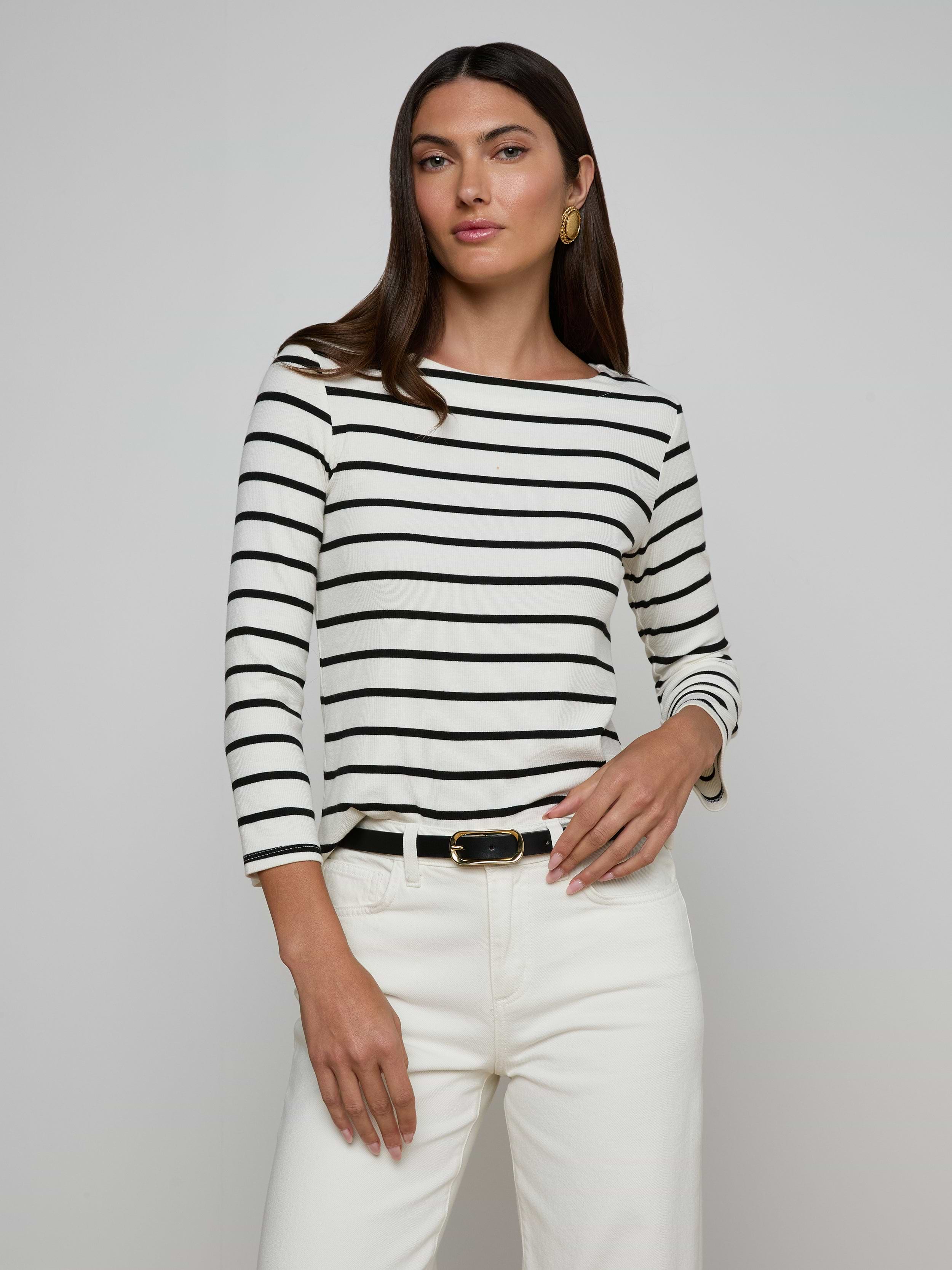 Woman wearing the Lucille Striped Boatneck Top paired with white pants and a black belt, posing against a plain light background.